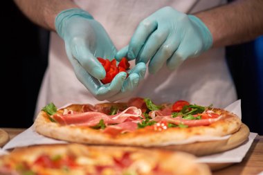 Şef ellerini et koyarak yakın bir görünüm de bir parma veya prosciutto jambon İtalyan pizza yapma. seçici odaklama.