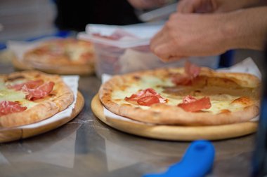 Şef ellerini et koyarak yakın bir görünüm de bir parma veya prosciutto jambon İtalyan pizza yapma. seçici odaklama.
