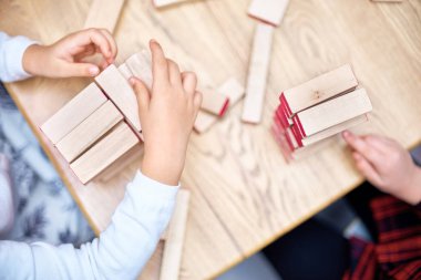 Çocuk ahşap çubukları kulede çalış. Kat ahşap parçaları. Çocuk kulenin katları çubuklardan dışarı alır. Tahta oyunu. Öğrenme ve eğitim kavramı. Üstten görünüm