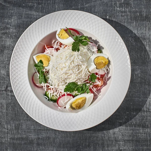 Ensalada con huevos, queso y verduras de primavera, rábanos con tomates. primer plano sobre la mesa . — Foto de Stock