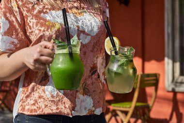 İki limonata kızın elinde. taze salatalık ve limon içecek. Yakın çekim.