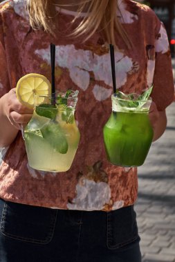 İki limonata kızın elinde. taze salatalık ve limon içecek. Yakın çekim.