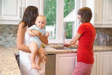 Annelik, Dadı, bebeklik ve çocukluk kavramı. Mutfak kapalı atış. İki kadın ve bir bebek onların kollarında kameraya bakarak ve dil, mutlu bir aile gösterilen