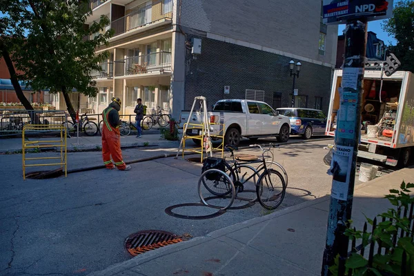 Montreal, Quebec, Canadá 25 de septiembre de 2018: Trabajador con chaleco de seguridad y cono naranja en la boca de inspección en la calle residencial —  Fotos de Stock