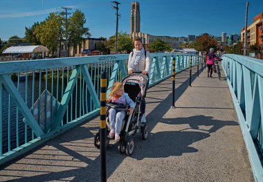 Montreal, Kanada - 2 Haziran 2016: Bebek arabası ve küçük bir kız lachine kanalı üzerindeki köprüden geçiyor