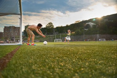 Montreal, Quebec, Kanada, 1 Eylül 2018: McGill Üniversitesi açık sahasında futbol. Kız ve ağabeyi topla oynuyorlar. Elbiseli küçük kız, adam çıplak.