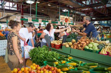 Montreal, Quebec, Kanada 29 Eylül 2018: Jean-Talon çiftçi pazarında meyve ve sebze standlarından ürün satın alan kadın. Kanada'da seyahat ederken mutlu bir yaşam tarzı yaşamak