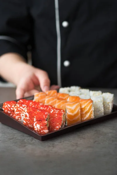 Sushi set on a plastic container is ready to pick up the client. Sushi delivery, cook prepared sushi to go.