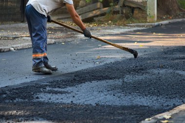 İşçi, yeni yol inşaatında yeni asfalt yol inşa etme sürecini yürütüyor