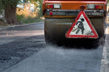 Silindirin altında sıcak asfalt dumanlar. Yol yapımı. Yol onarımı.