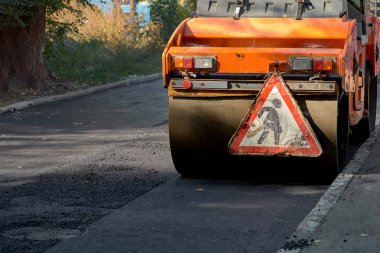 Silindirin altında sıcak asfalt dumanlar. Yol yapımı. Yol onarımı.