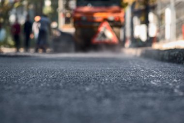 Bulanık arka plan, onarım yolları. Yol yapımı. Yeni, sadece asfalt döşenmiş, yolda bir ağaçyaprakları.