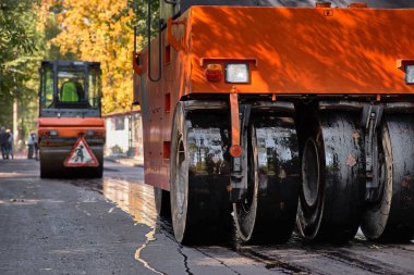 Silindirin altında sıcak asfalt dumanlar. Yol yapımı. Yol onarımı.