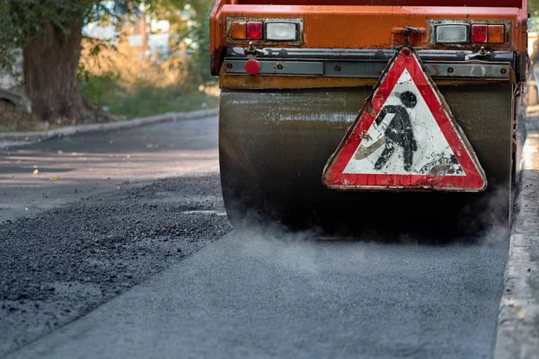 El asfalto caliente fuma bajo el rodillo. Construcción de carreteras.Reparación de carreteras . —  Fotos de Stock
