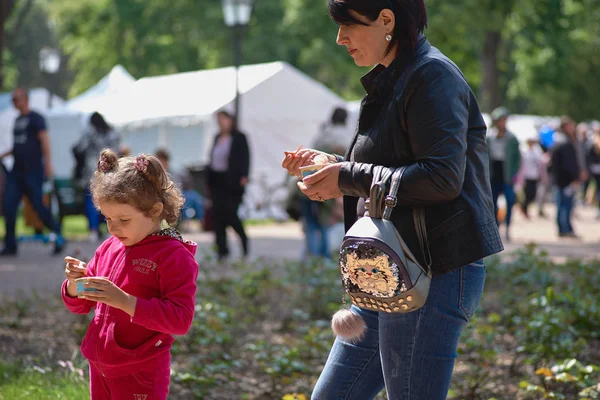 Chisinau, République de Moldavie - 10 mai 2019 : la crème glacée est distribuée gratuitement, une femme joyeuse donne à son enfant de la crème glacée. Célébration de la Journée de l'Europe à Chisinau, Moldova — Photo