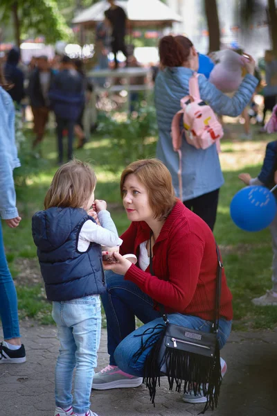 Chisinau, République de Moldavie - 10 mai 2019 : la crème glacée est distribuée gratuitement, une femme joyeuse donne à son enfant de la crème glacée. Célébration de la Journée de l'Europe à Chisinau, Moldova — Photo
