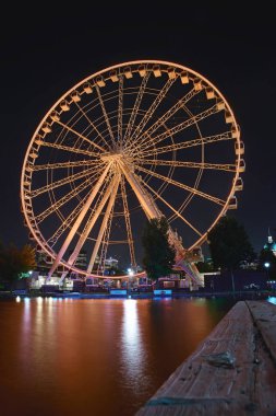 Montreal, Quebec, Kanada, 6 Eylül 2018: Gece dönme dolap oranzhennogo renk suda yansıması ile. Montreal, Quebec, Kanada'nın eski limanında çekildi.