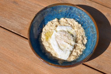 Masanın üzerinde mavi bir tabakta Sabah Kahvaltısı. kızarmış yumurta ile tuzlu yulaf ezmesi, üst görünümü. Sağlıklı dengeli kahvaltı gıda