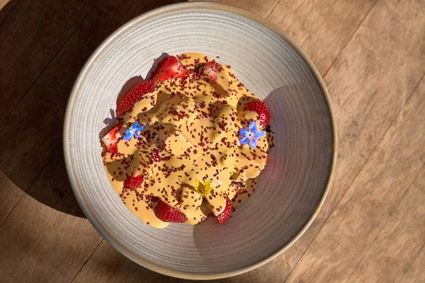 Ochtend ontbijt in een blauwe plaat op de tafel. Roomijs met karamel en verse aardbeien. selectieve focus. — Stockfoto