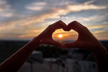 Kavram veya kavramsal kadın elleri aşık, Montreal arka plan üzerinde kalp sembolü. Parlak günbatımı ve güneşli altın karşı ellerin kalp şekli yapma