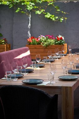 Konuklar için güneşlenme terasında büyük bir masa. Restoran ziyaretçileri için masada mavi tabaklar ve gözlükler var. Yakın çekim