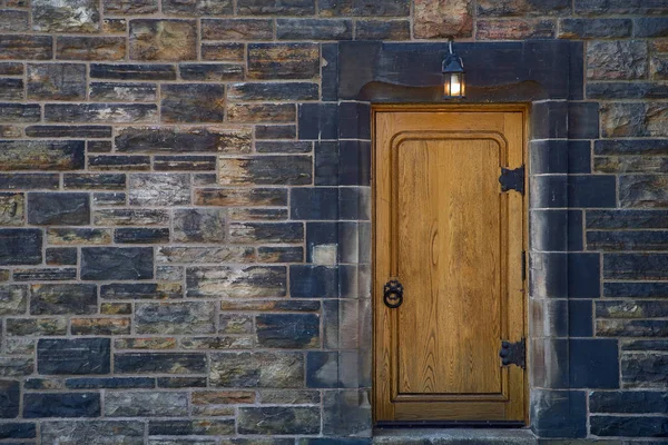 Тяжелые закрытые двери желтого цвета на каменной стене средневековой крепости, сделанные из клепальной древесины — стоковое фото