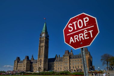 Ottawa, Kanada kentinde Kanada Parlamentosu arka plan aleyhine bir kırmızı ve beyaz, iki dilli İngilizce ve Fransızca durdurmak işareti Closeup.