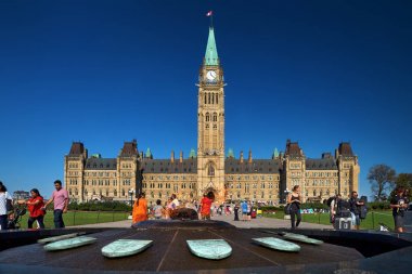 Ottawa, Ontario, Kanada 18 Eylül 2018: Merkez bloğun arka planına ve Parlamento Tepesi'ndeki Barış Kulesi'ne karşı yüzyıllık flam ve turistler, Ottawa, Kanada.