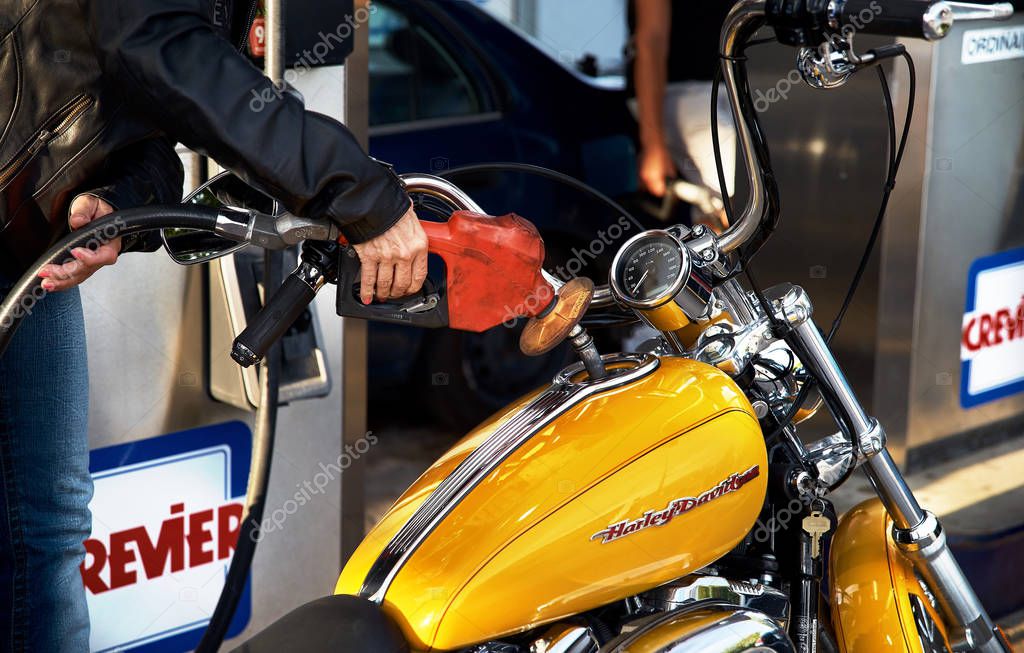 Montreal, Quebec, Canada, September 1, 2018. Woman hand close up tucking a Harley Davidson motorcycle at a gas station. old gas station in Crevier on the road to Ottawa from Montreal.