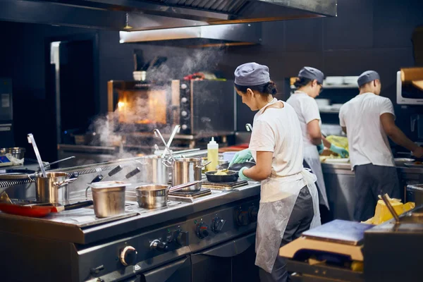El equipo de cocineros retrocede en el trabajo en la cocina moderna, el flujo de trabajo del restaurante en la cocina. Copiar espacio para texto — Foto de Stock