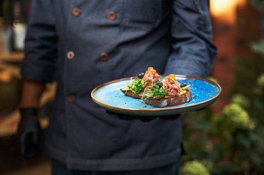 bruschette lezzetli çiğ sığır tartar, çanak mavi üniformalı bir aşçı tarafından elinde tutulur.