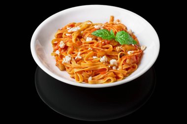 Taze fesleğen yaprakları ve peynir ile lezzetli İtalyan spagetti makarna Heaped plaka, siyah bir arka plan Izole