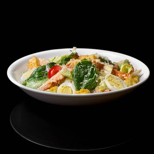 Sabrosa ensalada fresca apetitosa César con pollo, tomates, el queso de huevo parmesano en un tazón sobre fondo negro. Vista desde arriba . — Foto de Stock