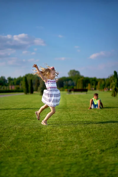 Dançando e pulando bonito menina no gramado no parque . — Fotografia de Stock