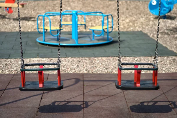 Two rubber swings weigh on a chain. Playground on a sunny day, shadow from the swing. Seats on the swing are free, there are no children on the Playground — Stock Photo, Image