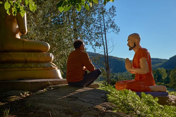 Ein 30-jähriger Mann in Lotusposition sitzt im Freien in der Nähe der Buddha-Statue in Quebec Harrington. Reise nach Kanada — Stockfoto