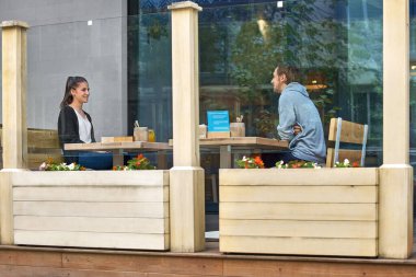 Genç çift yeni sosyal mesafe kurallarına göre terasta oturuyor. İnsanların virüsü azaltması için kavramsal yeni normal yaşam tarzı