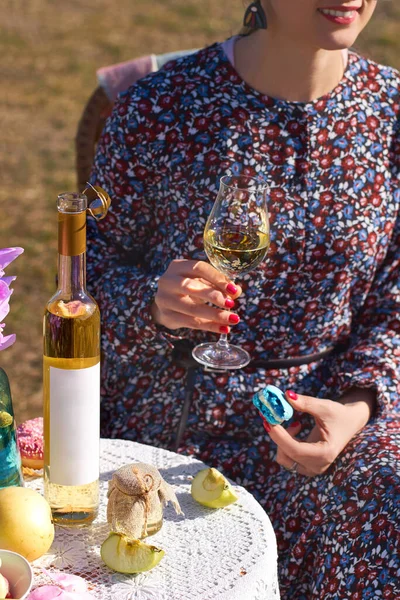 Draußen Tisch mit Teller mit Vorspeisen und Flasche mit leeren Etikette für Attrappen. Mädchen mit einem Glas Wein in der Hand an einem sonnigen Tag. — Stockfoto