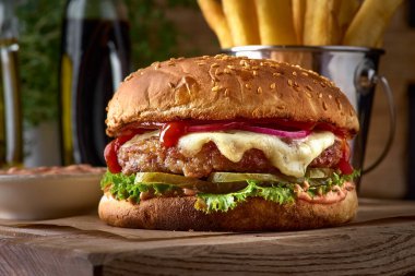 Fast food yemeği. İştah açıcı köfteler, patates cipsi ve sebze. Paket servis kompozisyonu. Tahtada patates kızartması, hamburger ve sos.