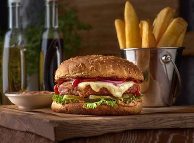 Fast food yemeği. İştah açıcı köfteler, patates cipsi ve sebze. Paket servis kompozisyonu. Tahtada patates kızartması, hamburger ve sos.