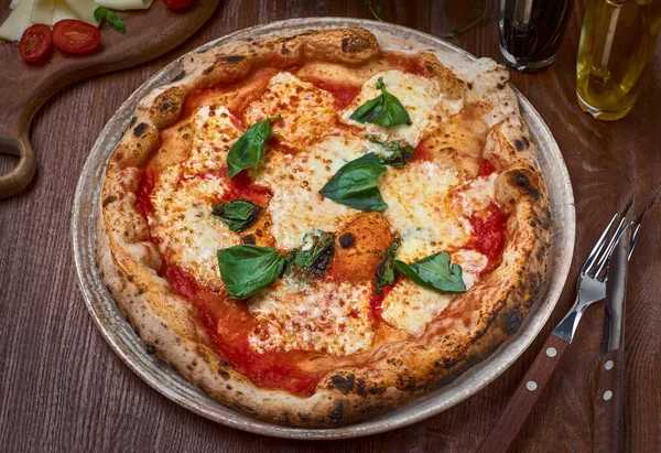 Domatesli, peynirli ve taze fesleğenli taze fırınlanmış Margherita pizzasının yüksek açılı görüntüsü.