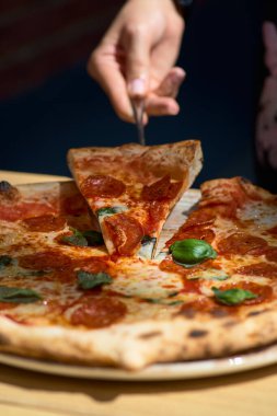 Sucuklu Amerikan pizzası, mozzarella ve domates sosu. Tahta bir masada pizza, sabah, şafak. Terasta. Yakın plan.