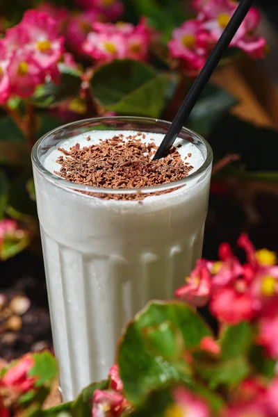 Çiçeklerin Arka Planında Çikolata Parçacıklı Milkshake — Stok fotoğraf