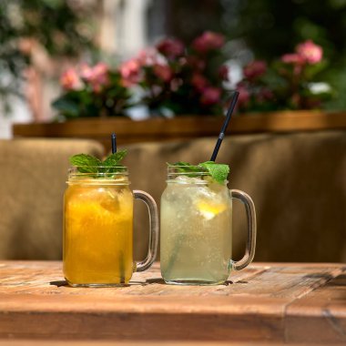 Soğuk ve ferahlatıcı limonata portakal, limon ve limonlu mason kavanozunda. Yazlık terasta güneşli bir gün