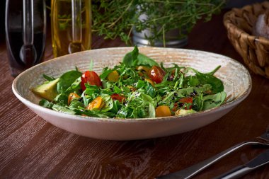 Yeşil yapraklardan, domateslerden ve zeytinyağıyla tatlandırılmış avokadodan yapılan besleyici düşük kalorili organik sebze salatası. Vücudun gerekli vitaminleri almasına ve mide çalışmasını normalleştirmesine yardımcı olur.