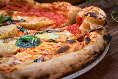 Enginarlı ve parmesanlı pizza, yakın plan iki dilim pizza, hamurun ve havanın hazır olduğunu gösteriyor..