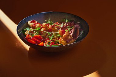 Izgara sığır eti ve avokado ile taze yaz salatası, karides ve turuncu arka planda muz kırıntıları. Alçak tuş