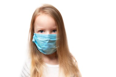 Yüzünde tıbbi maske olan 6 yaşındaki sarışın bir kızın portresi. Arka planda, yakın plan. Uzayı kopyala, hüzünlü bir bakış, virüsle ya da soğuk algınlığıyla savaş