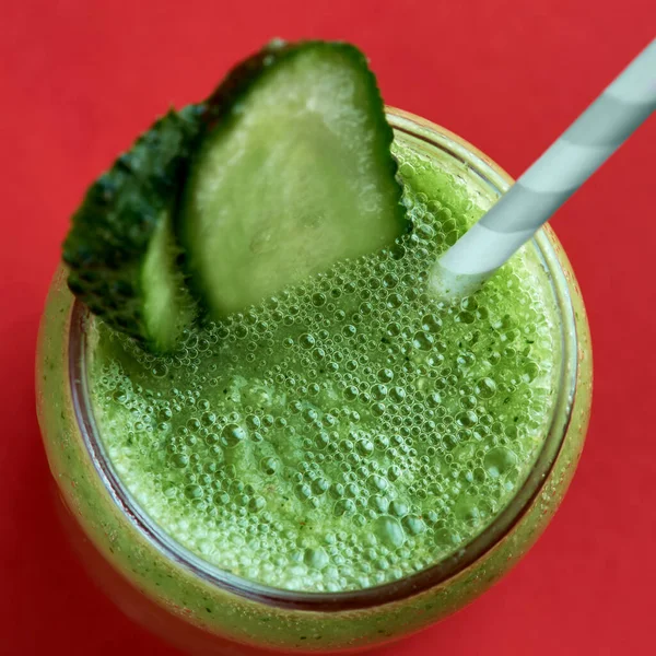 Smoothie vert avec concombre sur fond rouge — Photo