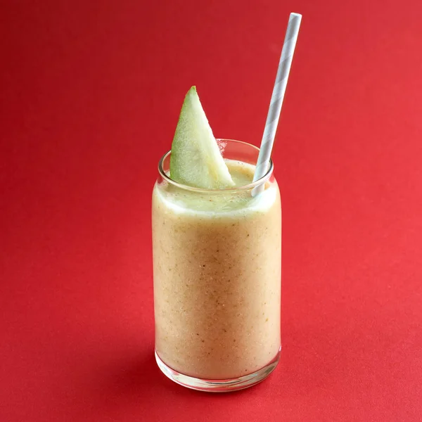 Smoothies Pêra feita a partir de mistura de frutas de pêra fresca com açúcar e leite, no fundo vermelho — Fotografia de Stock